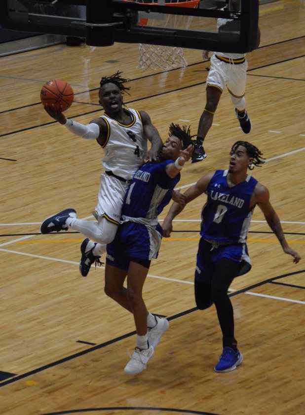 Skipper #4 Jakylen Thomas drives to the rim against two Lakeland defenders in early season competition. 