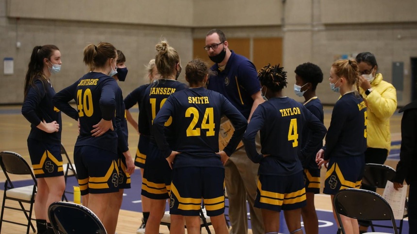 Coach archer and women's basketball team in huddle 