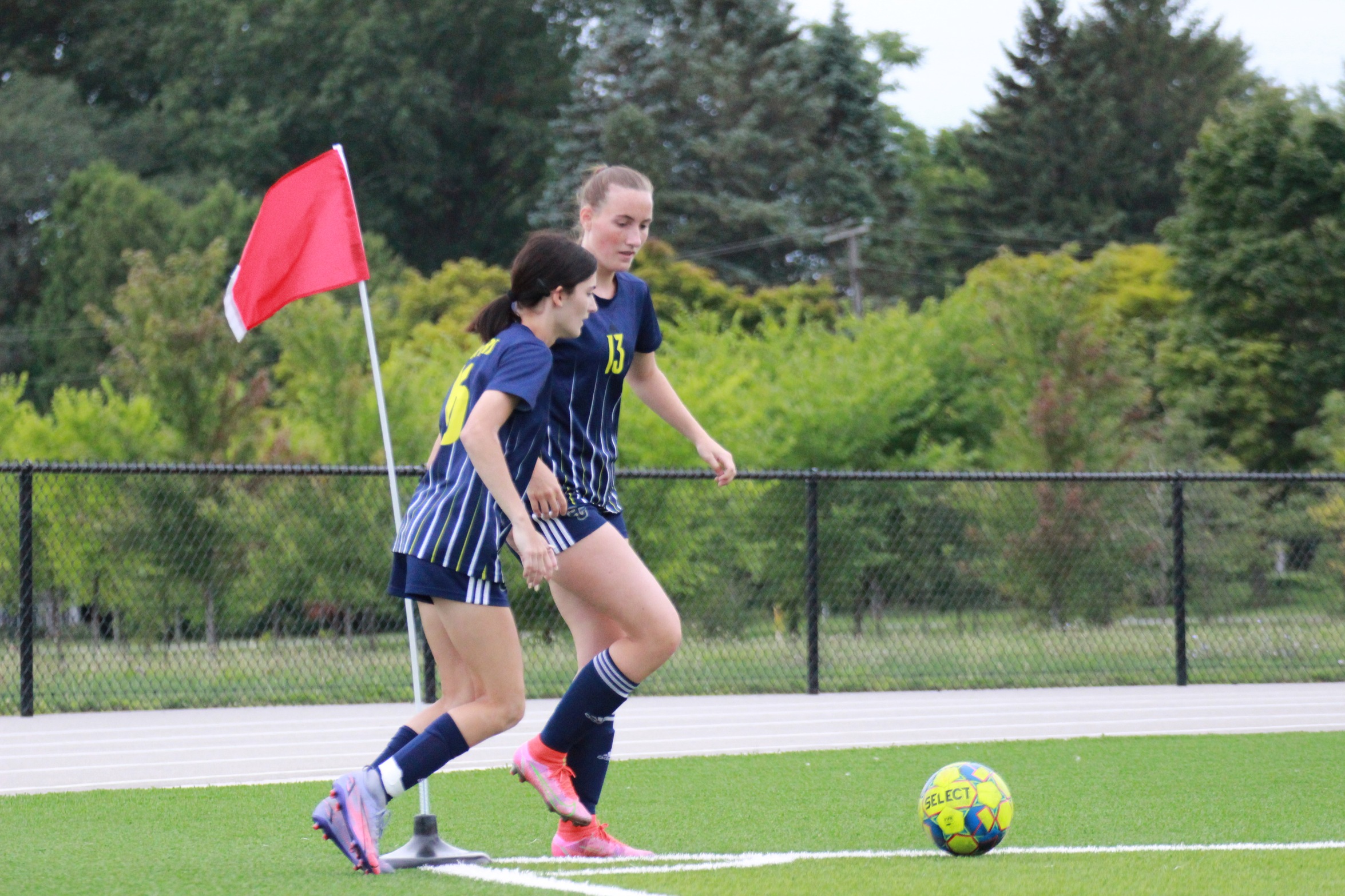 Jenna Peters and Hailey Dawson kicking a corner kick 